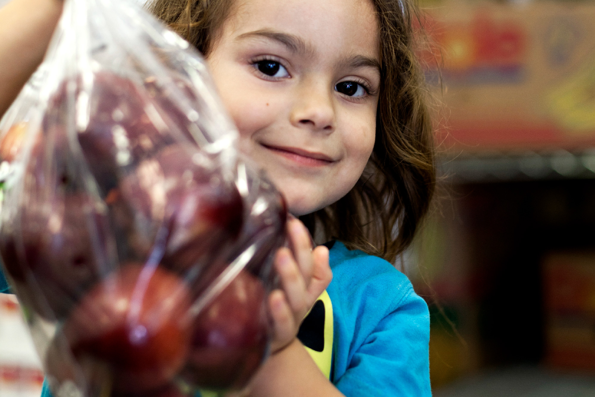 A young girl holds a bag of apples.