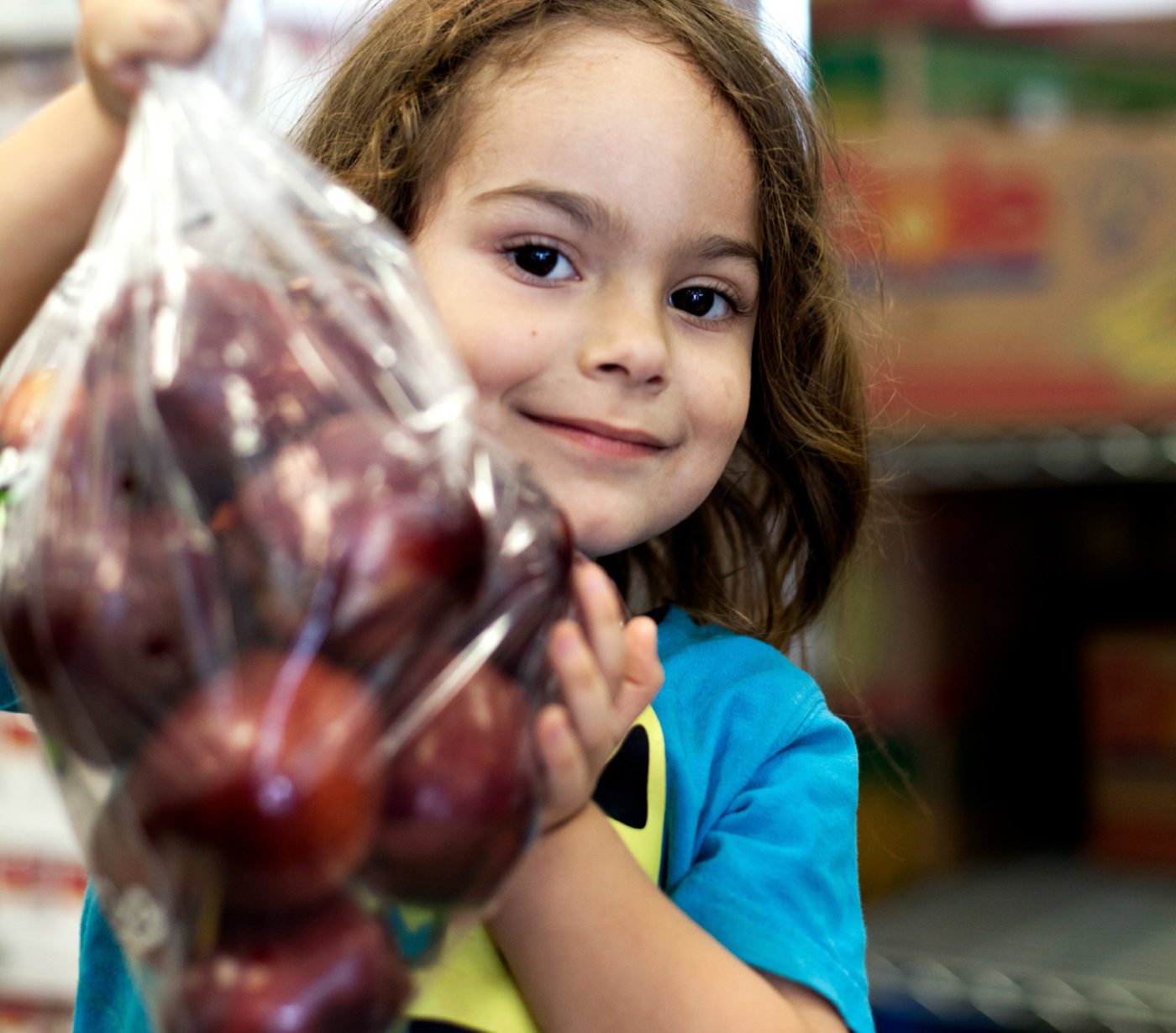 A young girl holds a bag of apples.