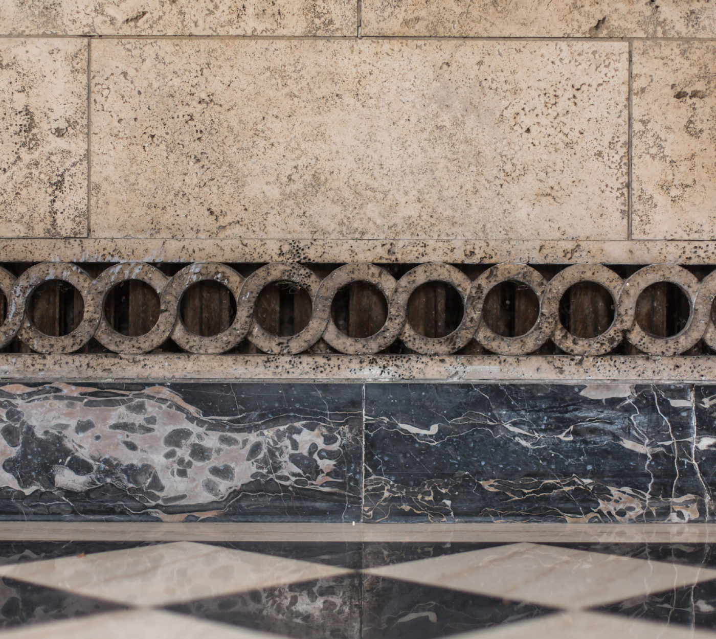 A detail photo of the carved marble baseboard and black and white alternating marble tiled floor.