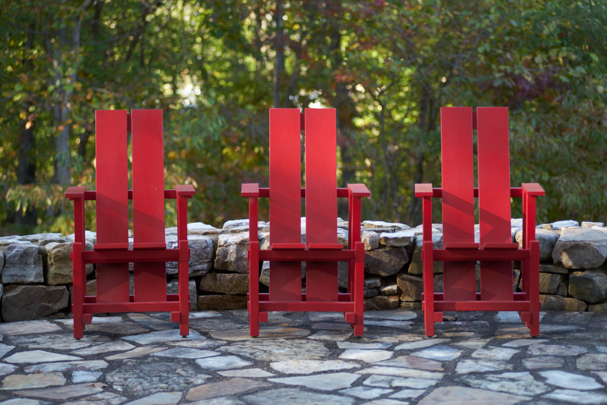 A photo of three red-painted Adirondack chairs at High Ground Park.