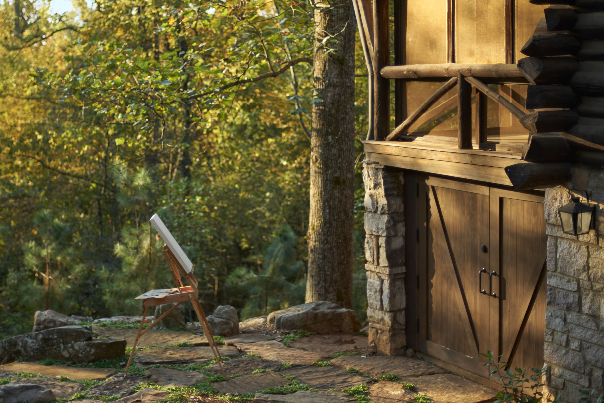 Photograph of a painter's easel holding an empty canvas sitting outside next to a Loghaven cabin.