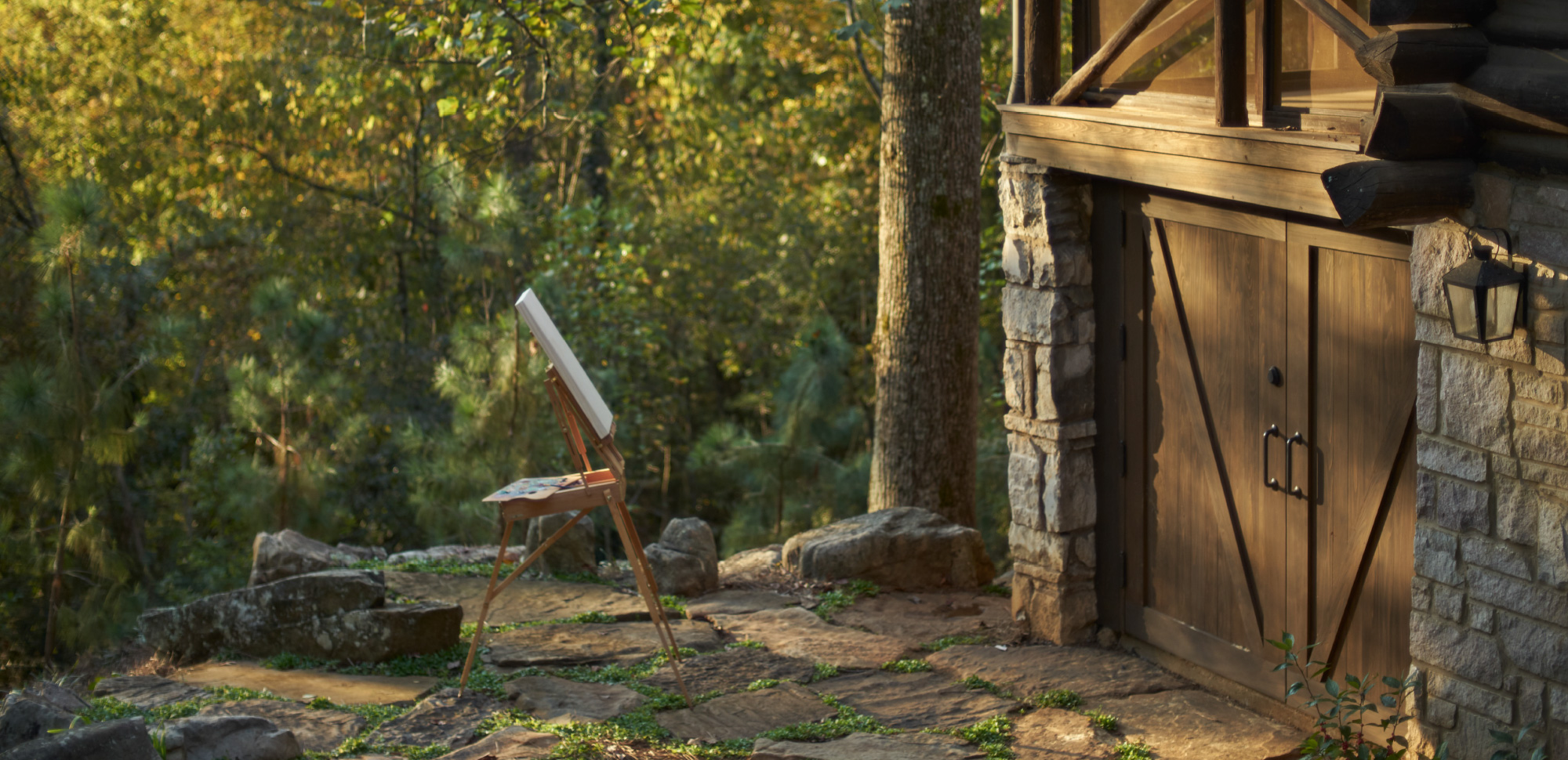 Photograph of a painter's easel holding an empty canvas sitting outside next to a Loghaven cabin.