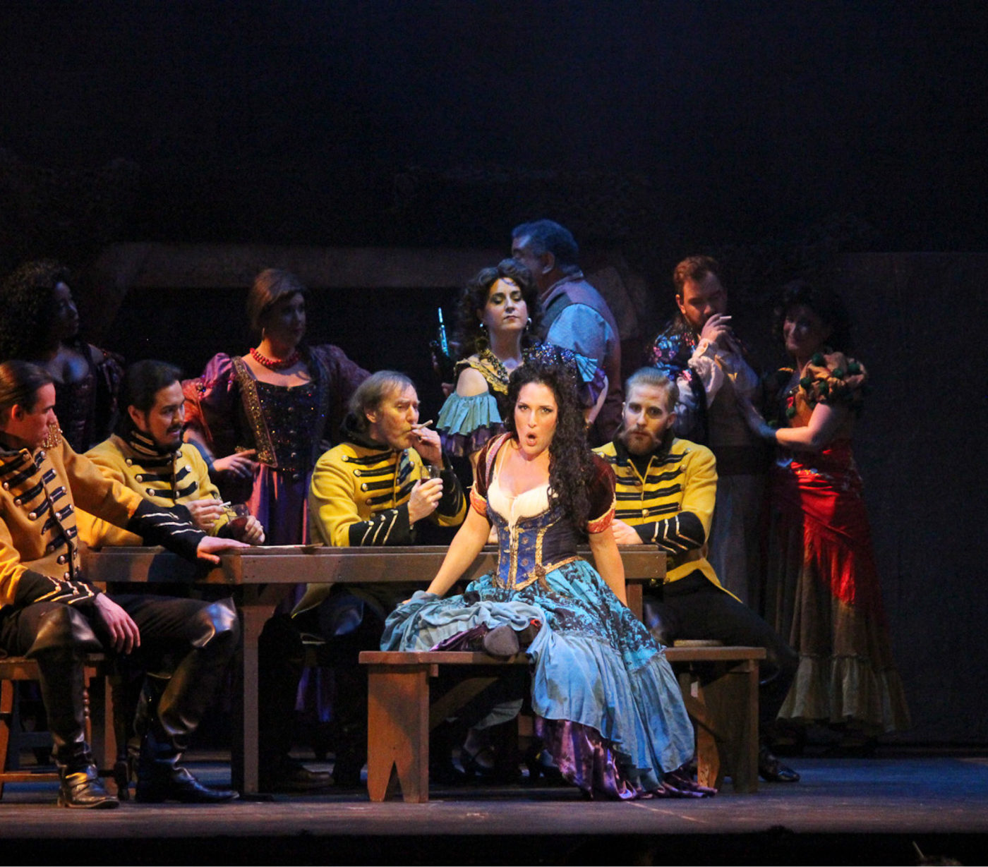 A soprano and cast members in 19th-century costume perform an opera onstage.