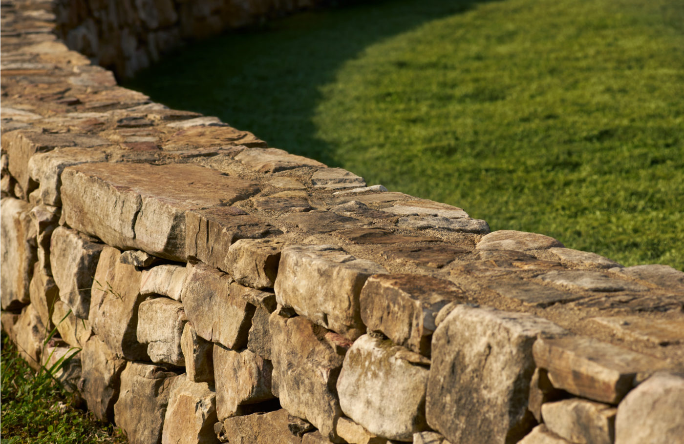 A detail photo of a low, curving stone wall.