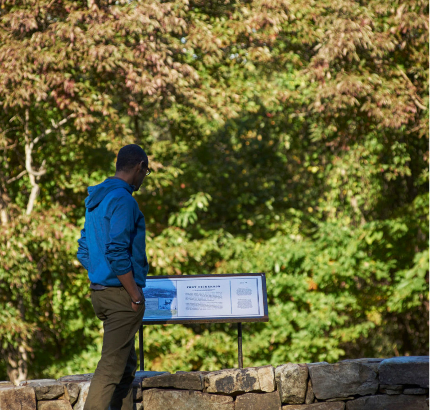 A man in a blue hoodie consults an information placard.