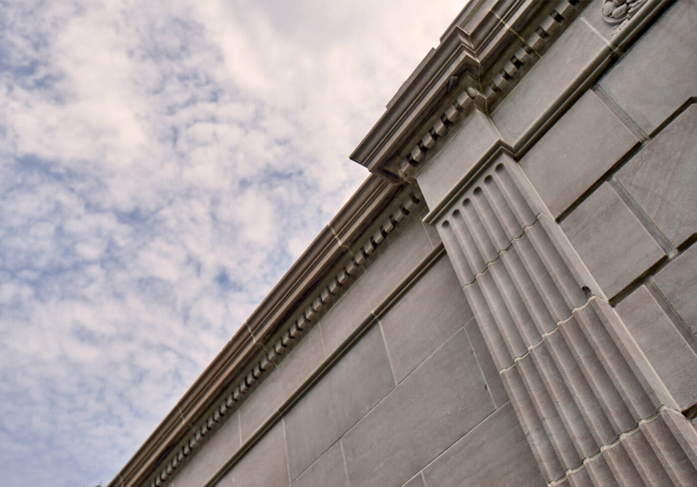 A photo looking upwards at an engaged fluted column, carved in marble, on the exterior of the building.