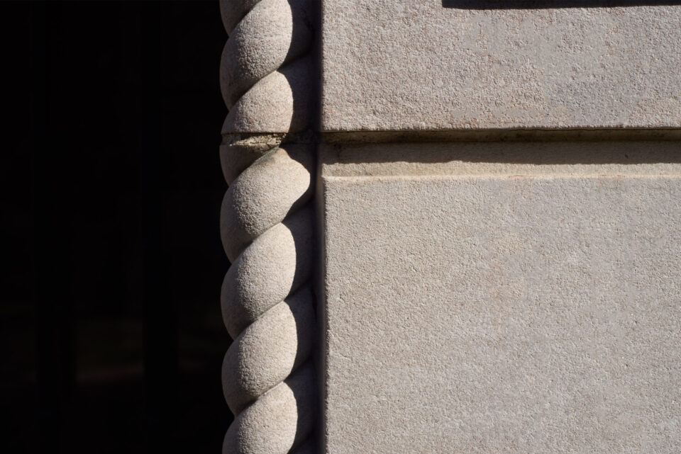 A detail of a carved marble rope feature on a corner of the building.