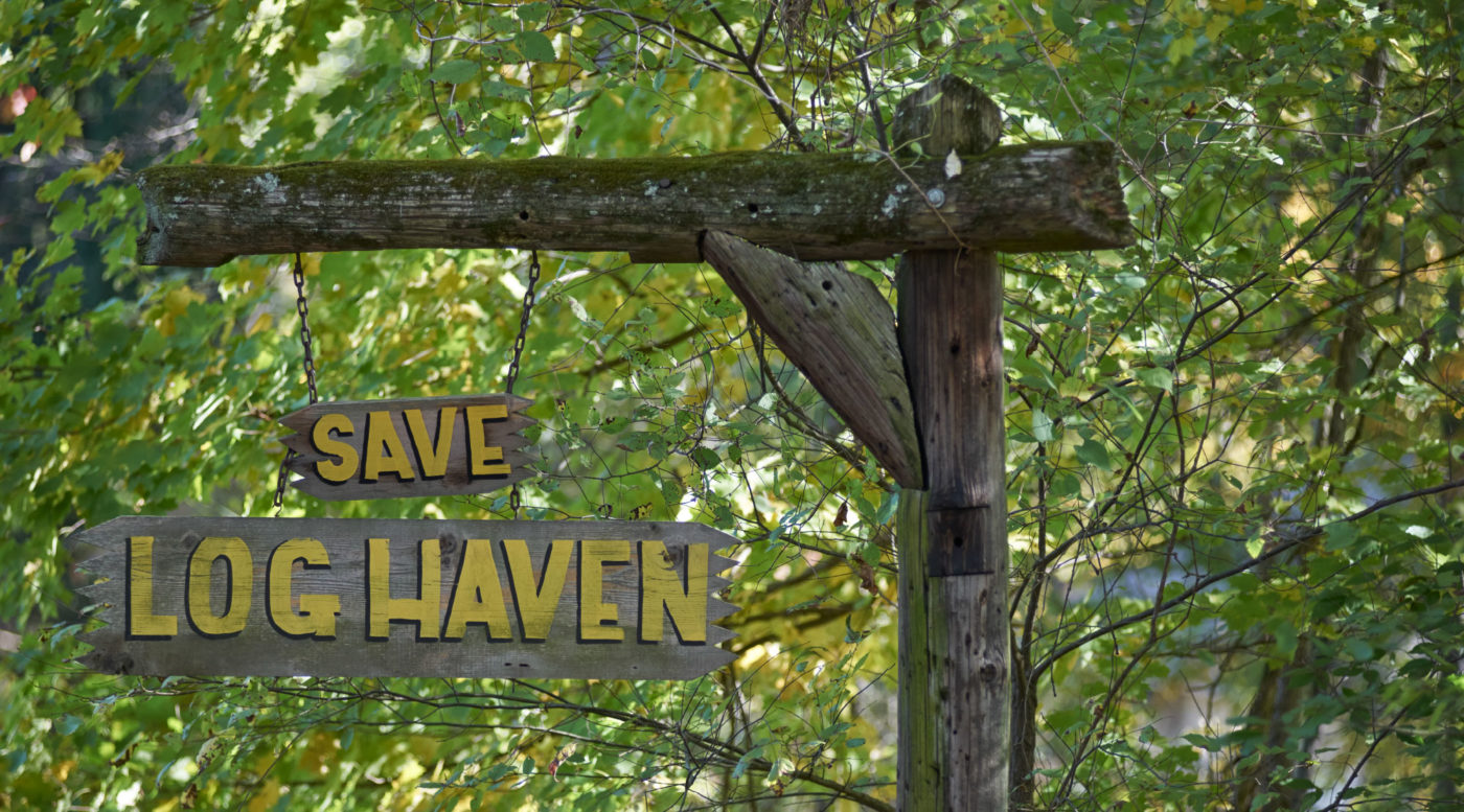 A rustic, wooden framed signpost reads 