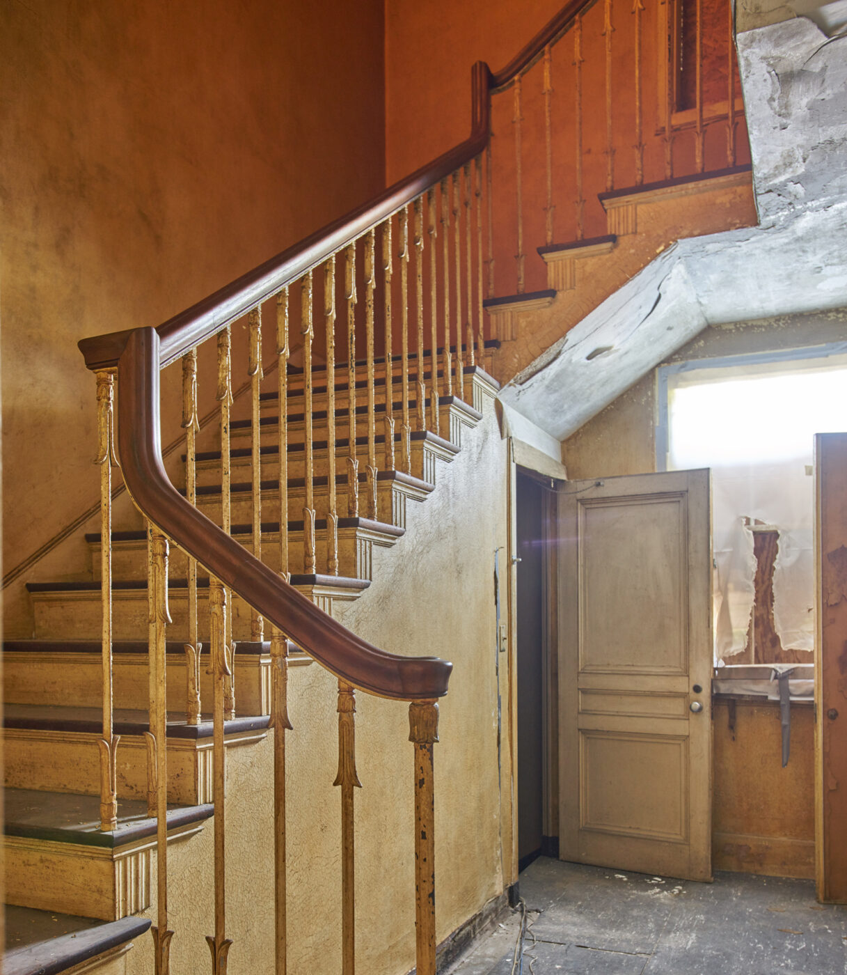 A photo looking up at a curving ornate staircase with a wooden railing.