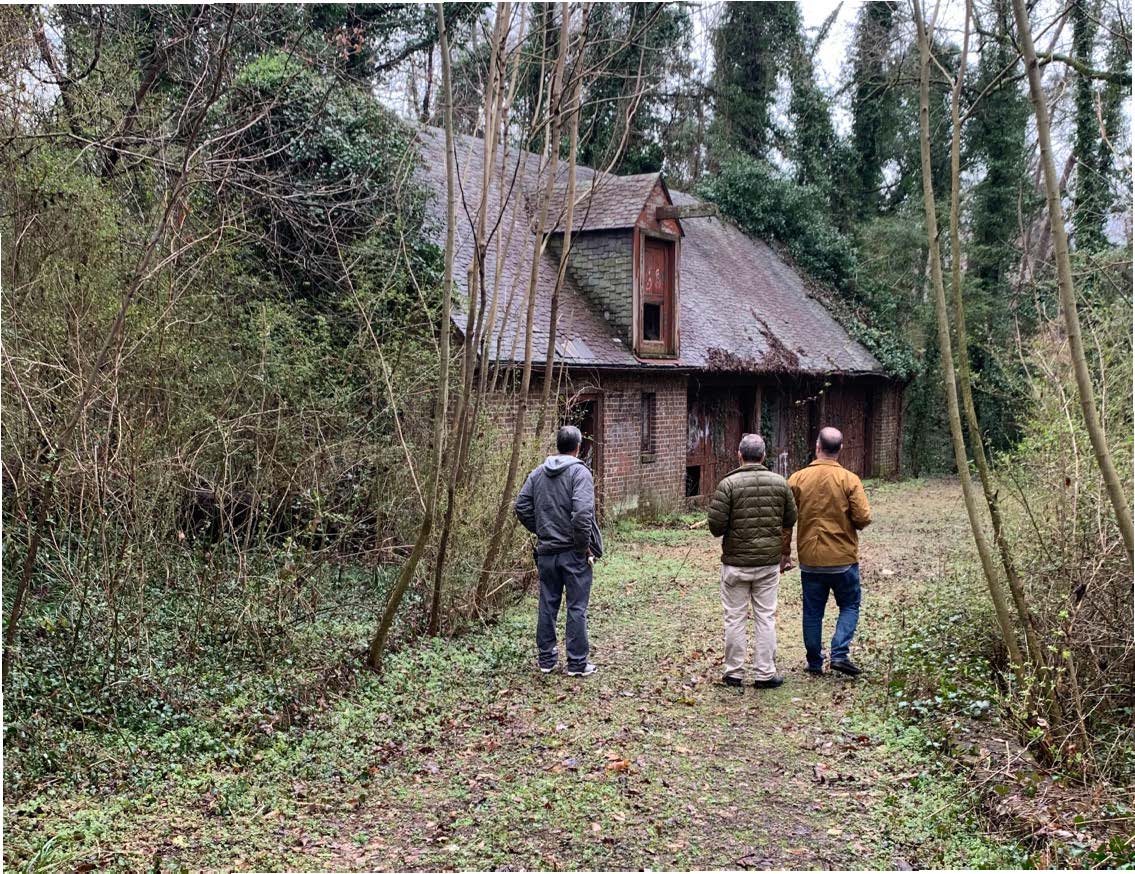 The architecture team walks towards the stable, which is in pre-restoration condition.