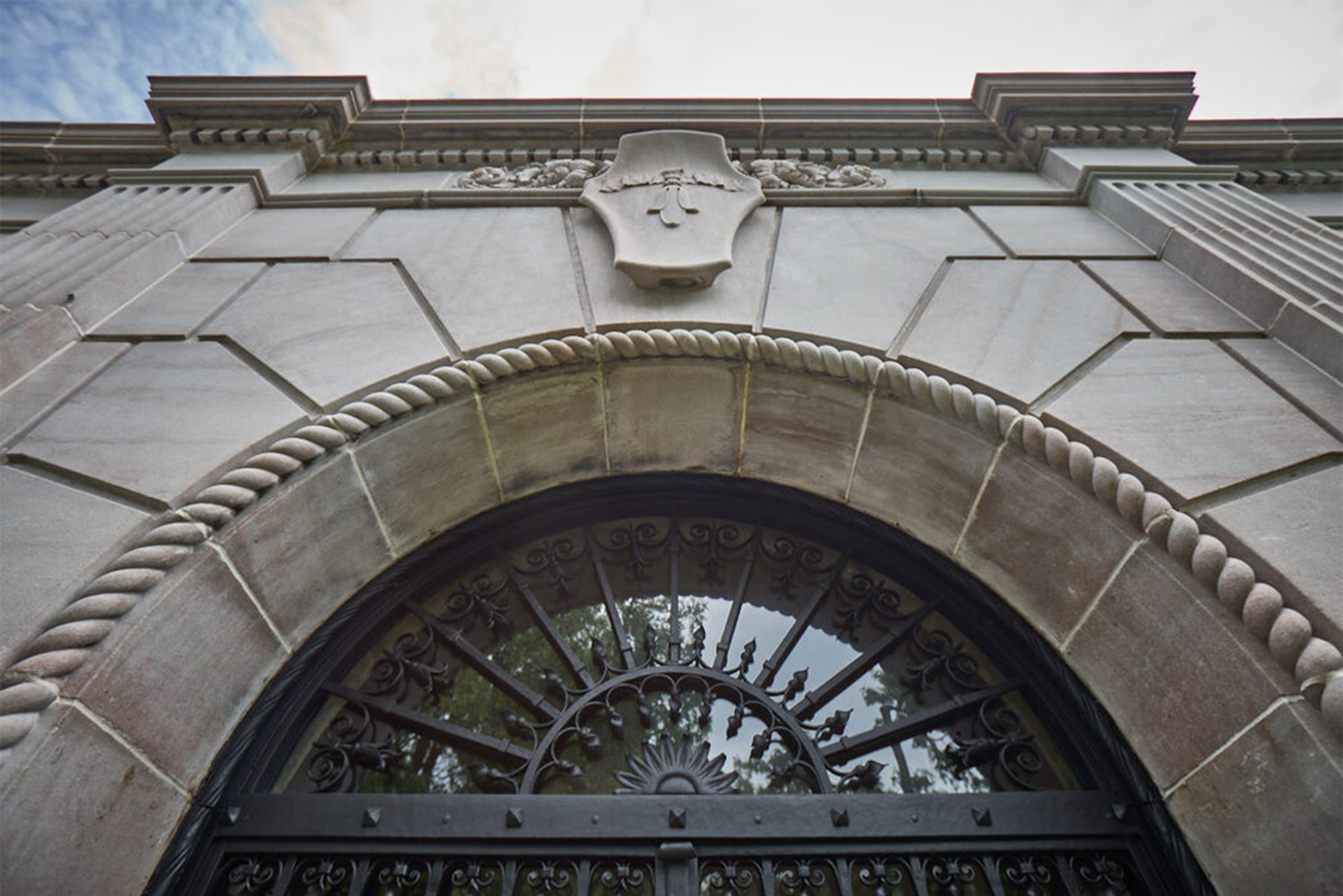 A photograph looks upwards at the front entrance of the Candoro Marble Building.